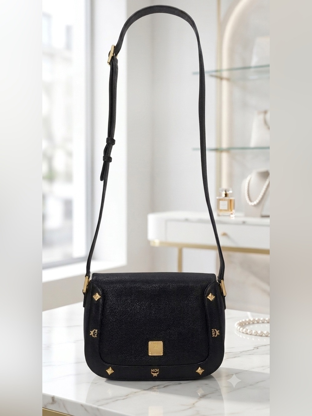 MCM crossbody bag featuring gold-tone hardware and stud embellishments.